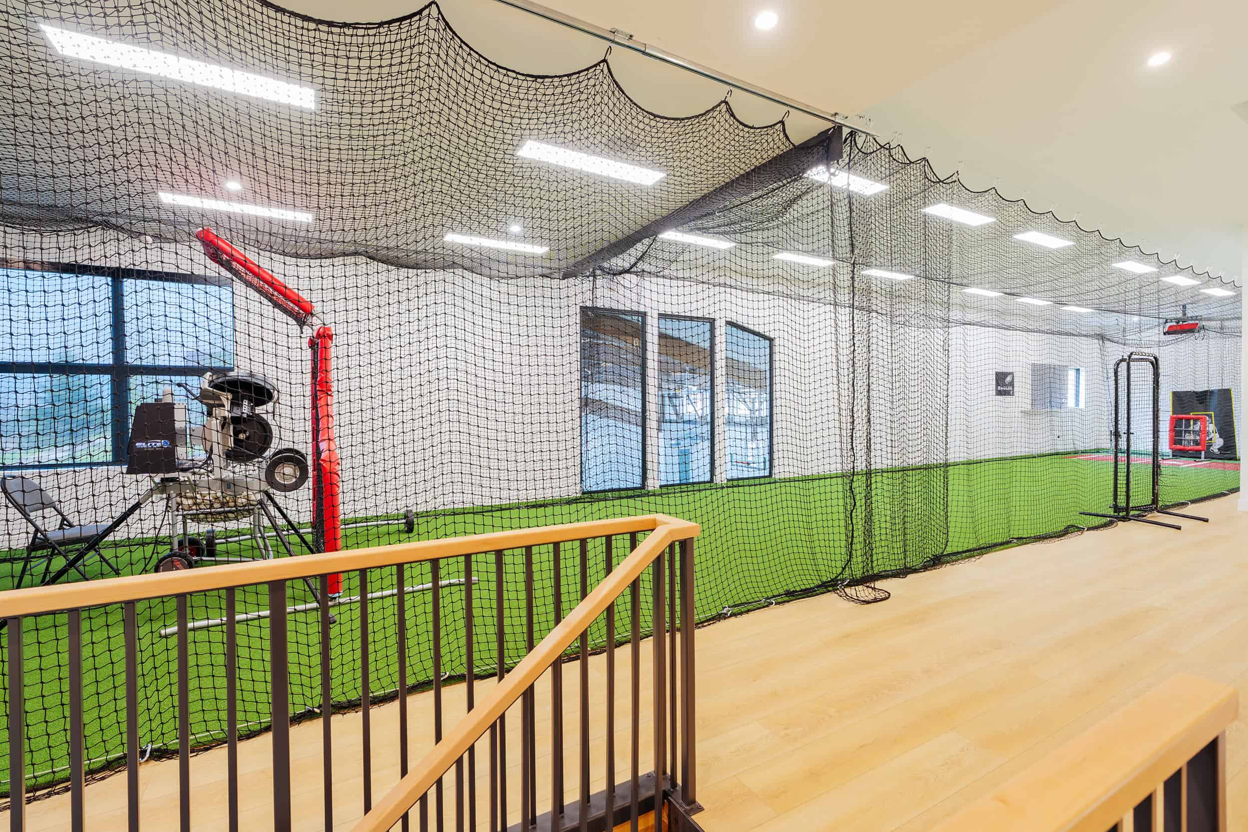 Indoor home batting cage, pitching machine, and agility equipment.
