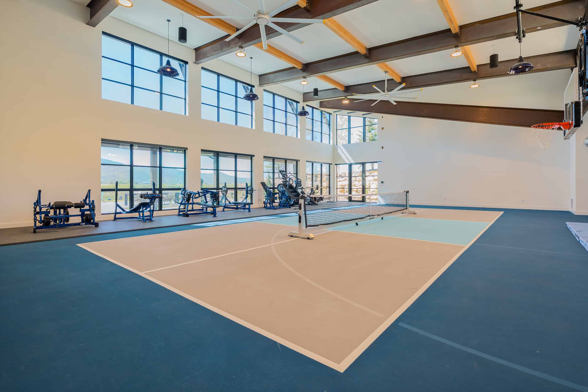 Bright indoor home sports gym with court, exercise equipment, and large windows for natural light in Park City.