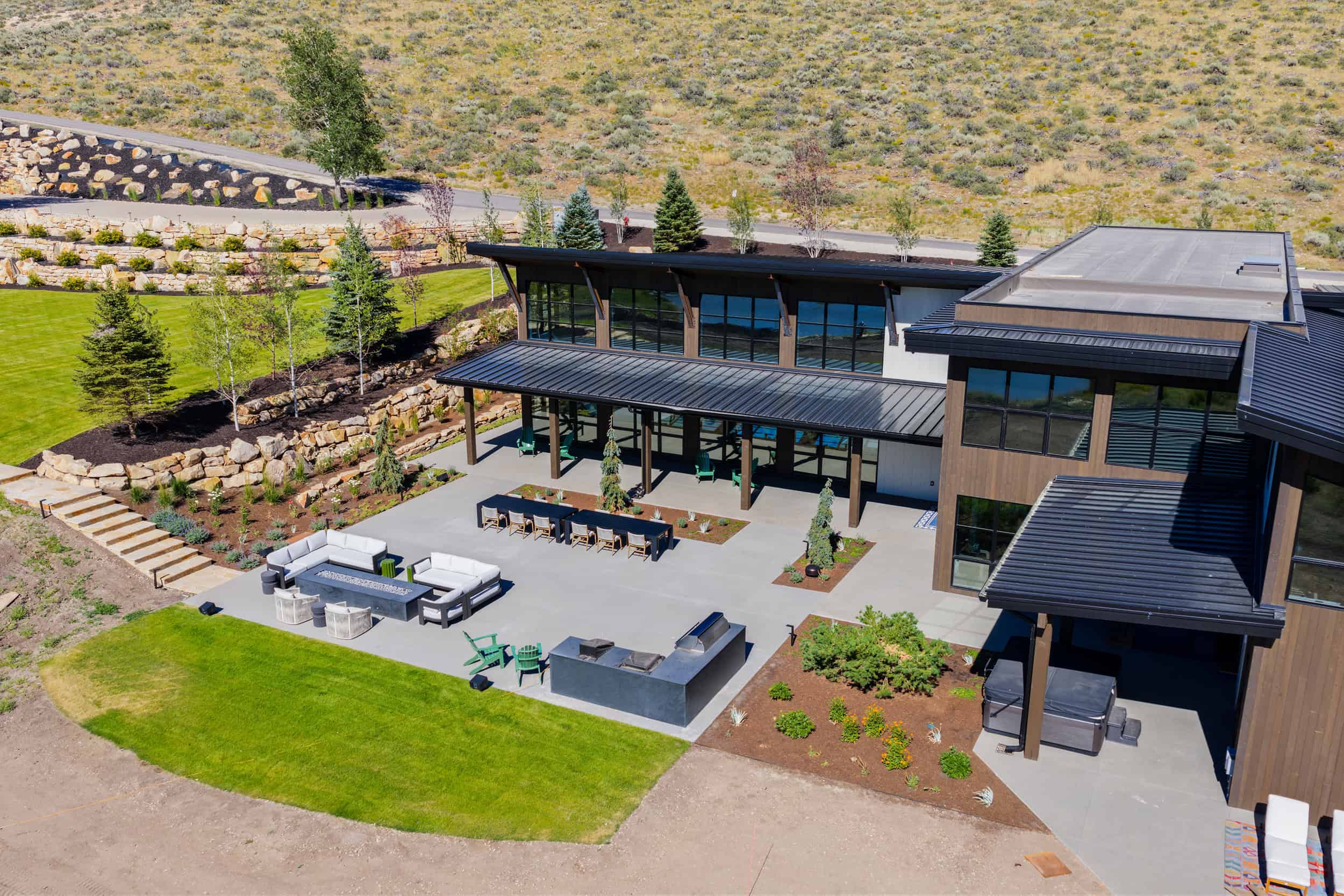 Stylish family home in Park City featuring spacious outdoor area with lounge, dining, and fire pit, surrounded by nature.