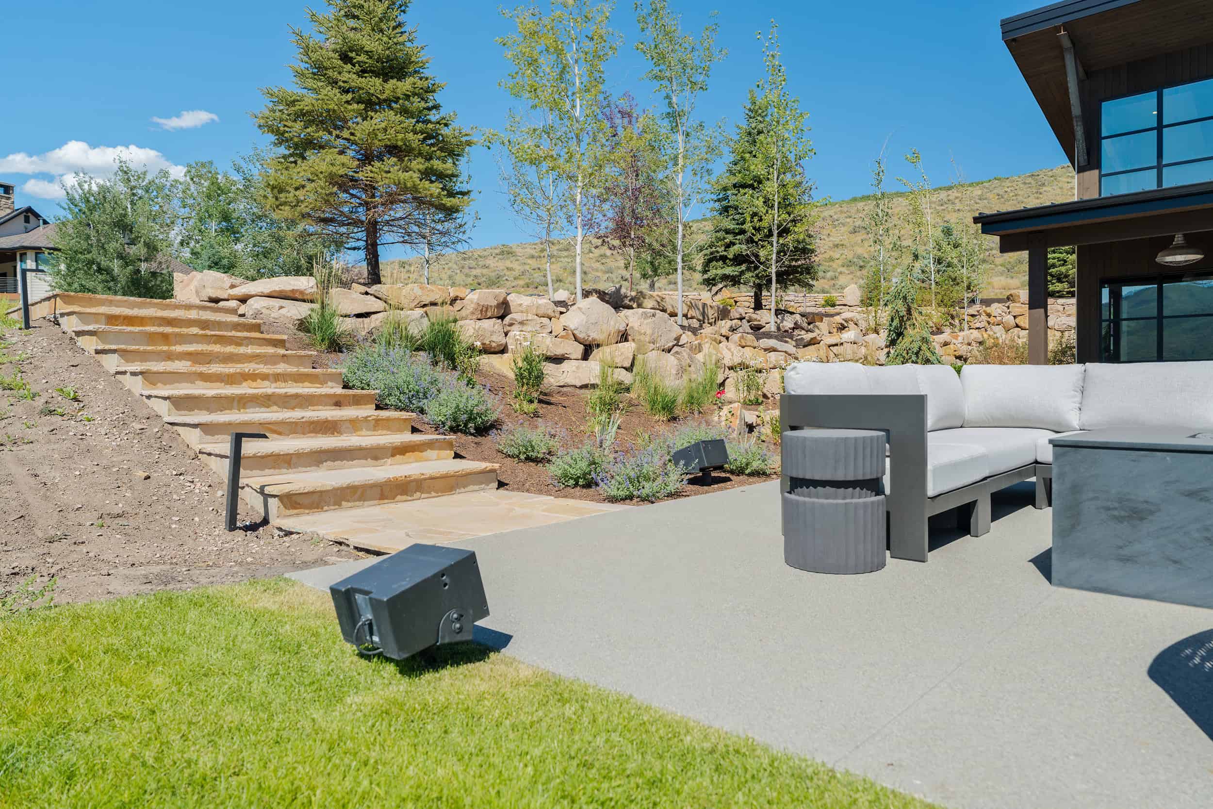 Stylish outdoor patio with modern seating, lush landscaping, and mountain views, perfect for entertaining and relaxation.