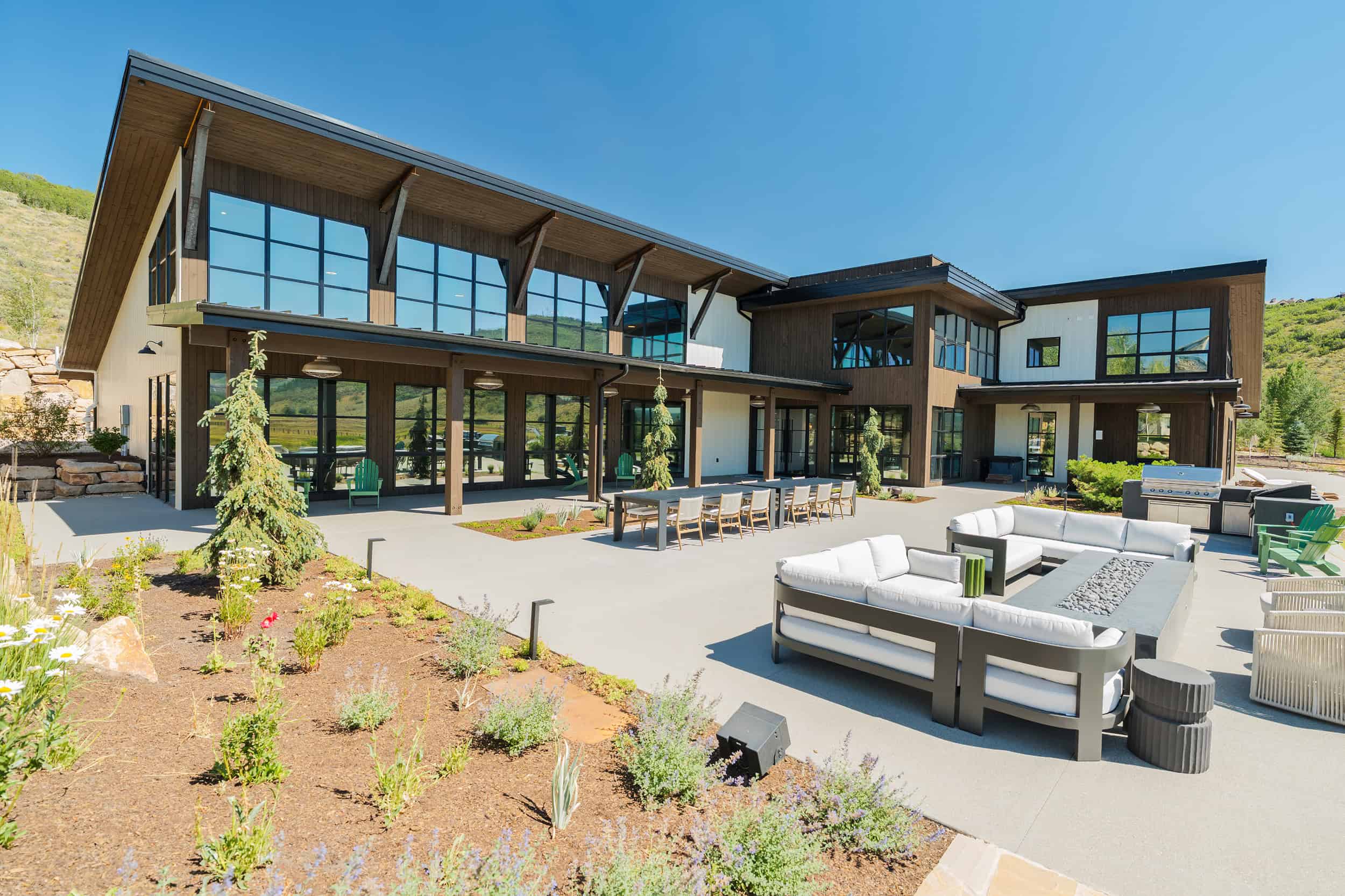 Abundant outdoor lounge area with contemporary furniture, fire pit, and barbecue grill at a scenic hillside home in Park City.