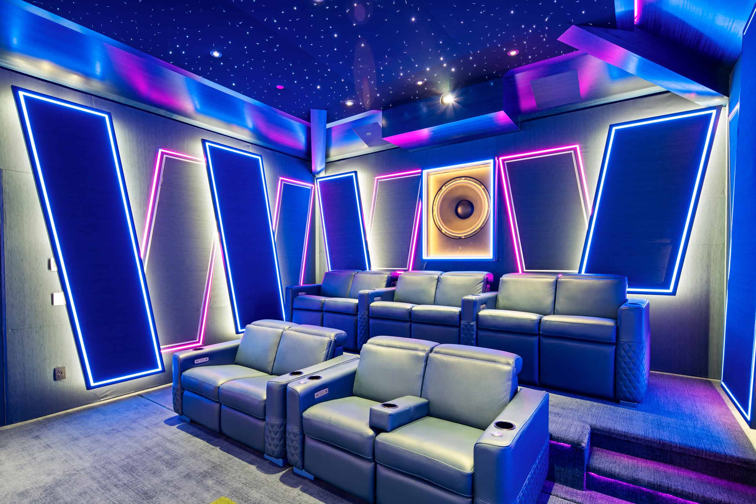 Bright, colorful home theater with modern leather recliners and dynamic wall lighting.